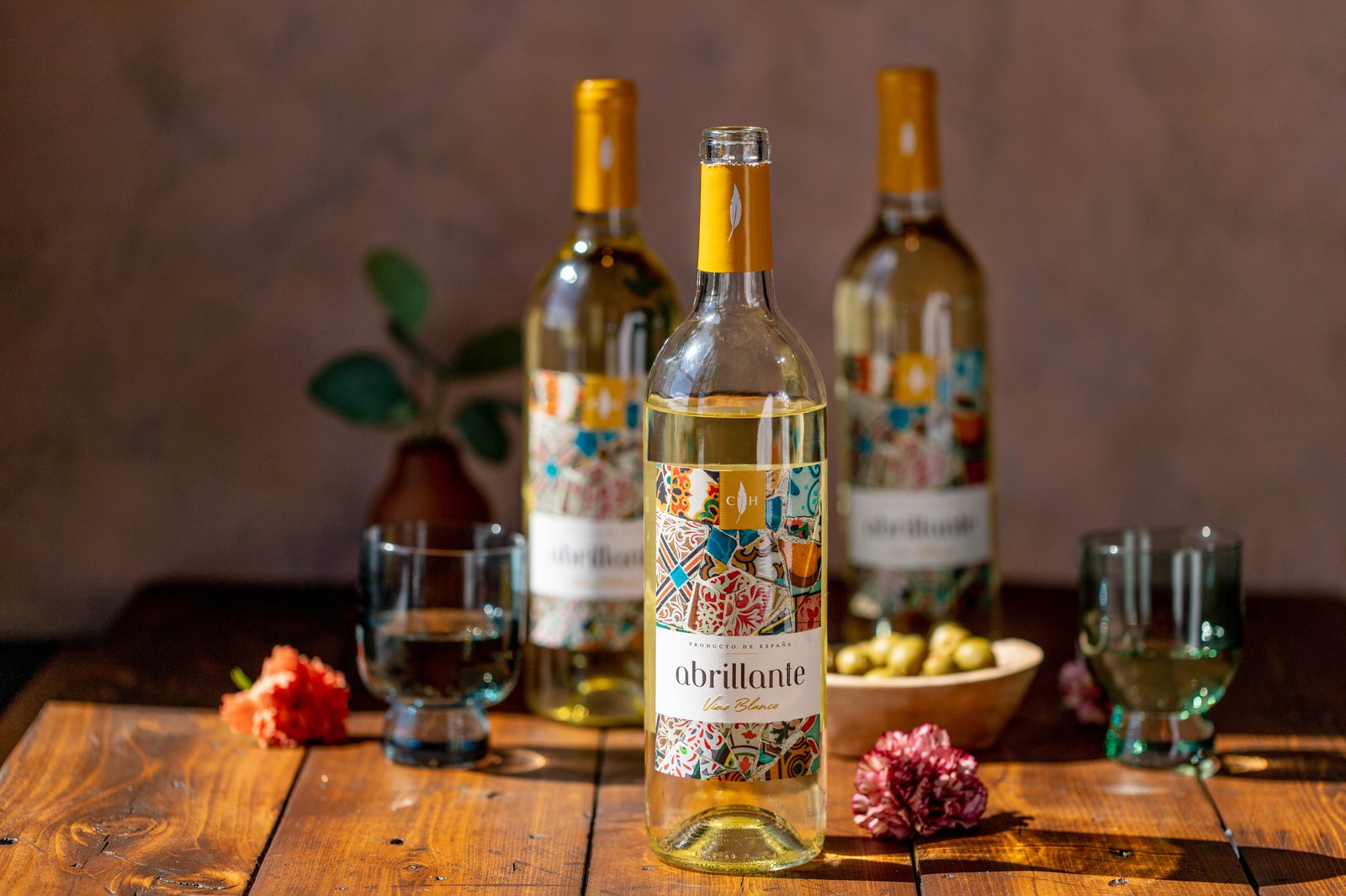 Three bottles of white wine on a wooden table.