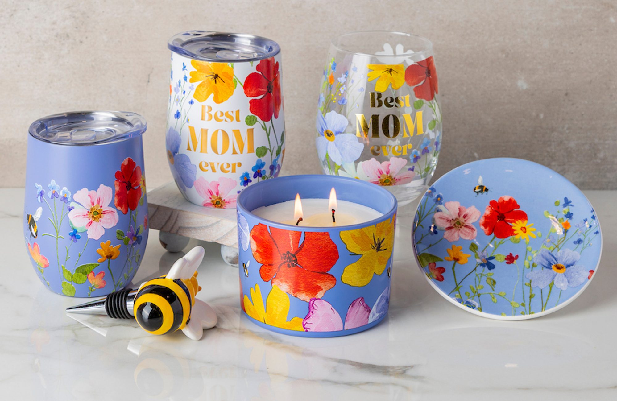 Floral tumblers and glasses—two read Best MOM ever; lit blue floral candle in tin, lid/dish, bee bottle stopper