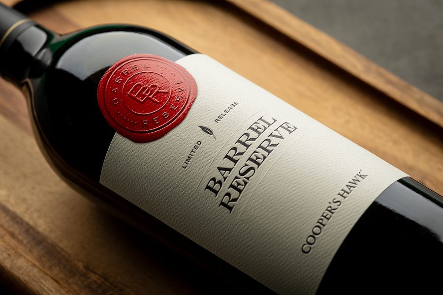 Cooper's Hawk Barrel Reserve wine bottle with white label and red wax seal on a wooden tray