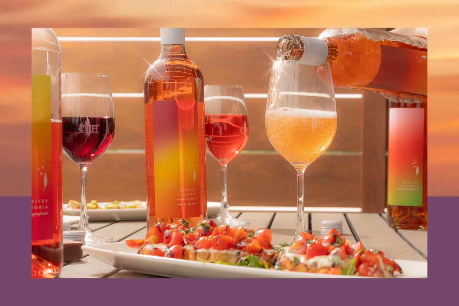 Pink spritzy sangria bottles and glasses, one being poured into a glass, with bruschetta appetizers