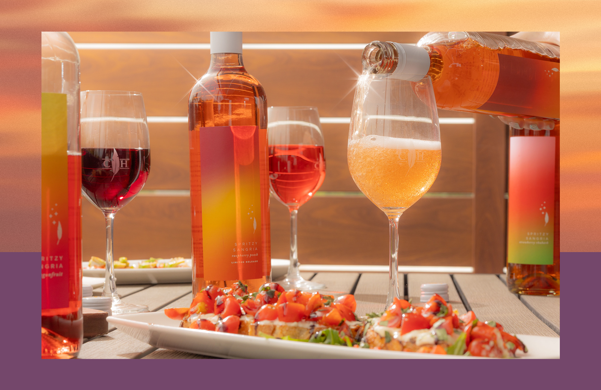 Pink spritzy sangria bottles and glasses, one being poured into a glass, with bruschetta appetizers