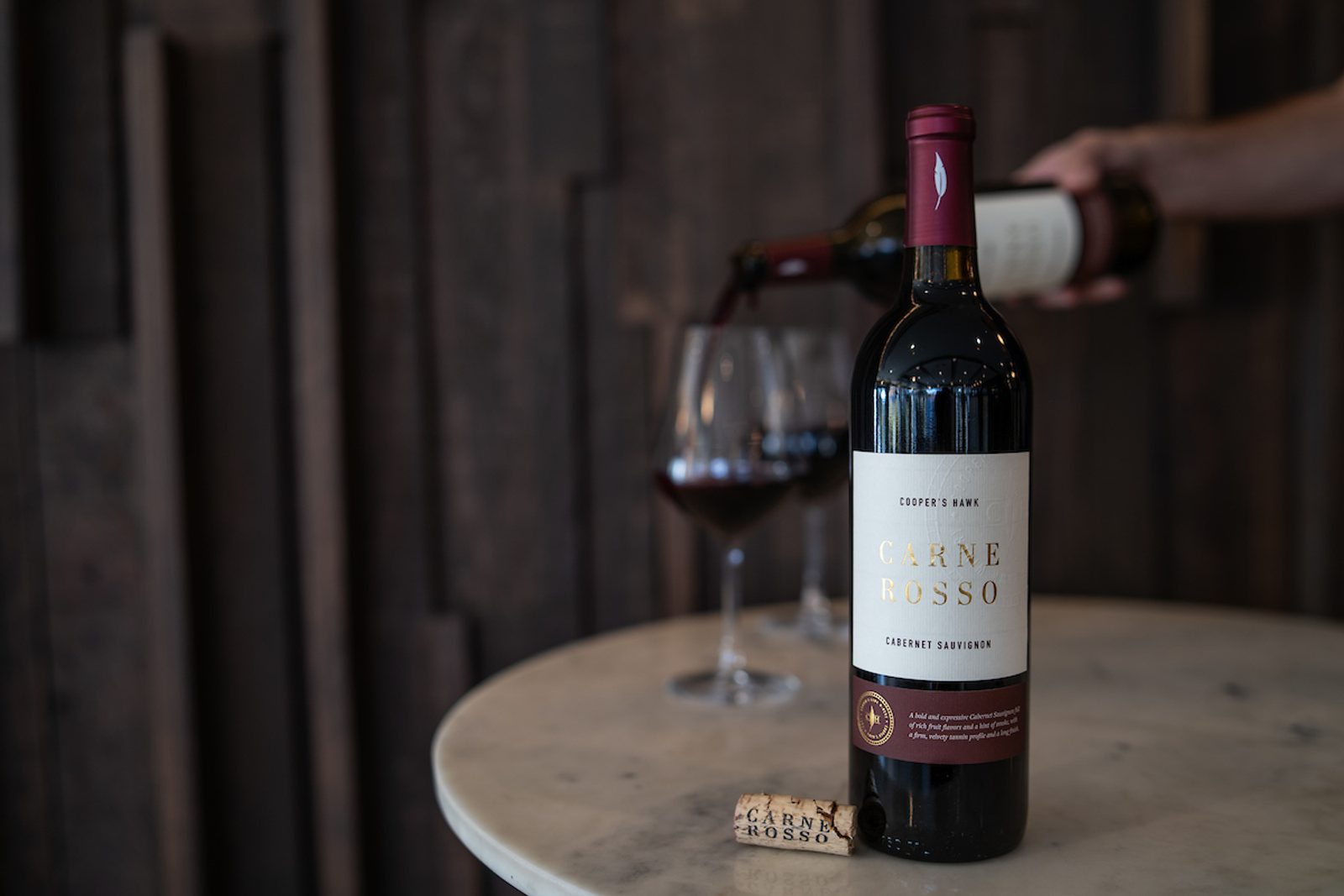 A bottle of wine being poured into a glass.