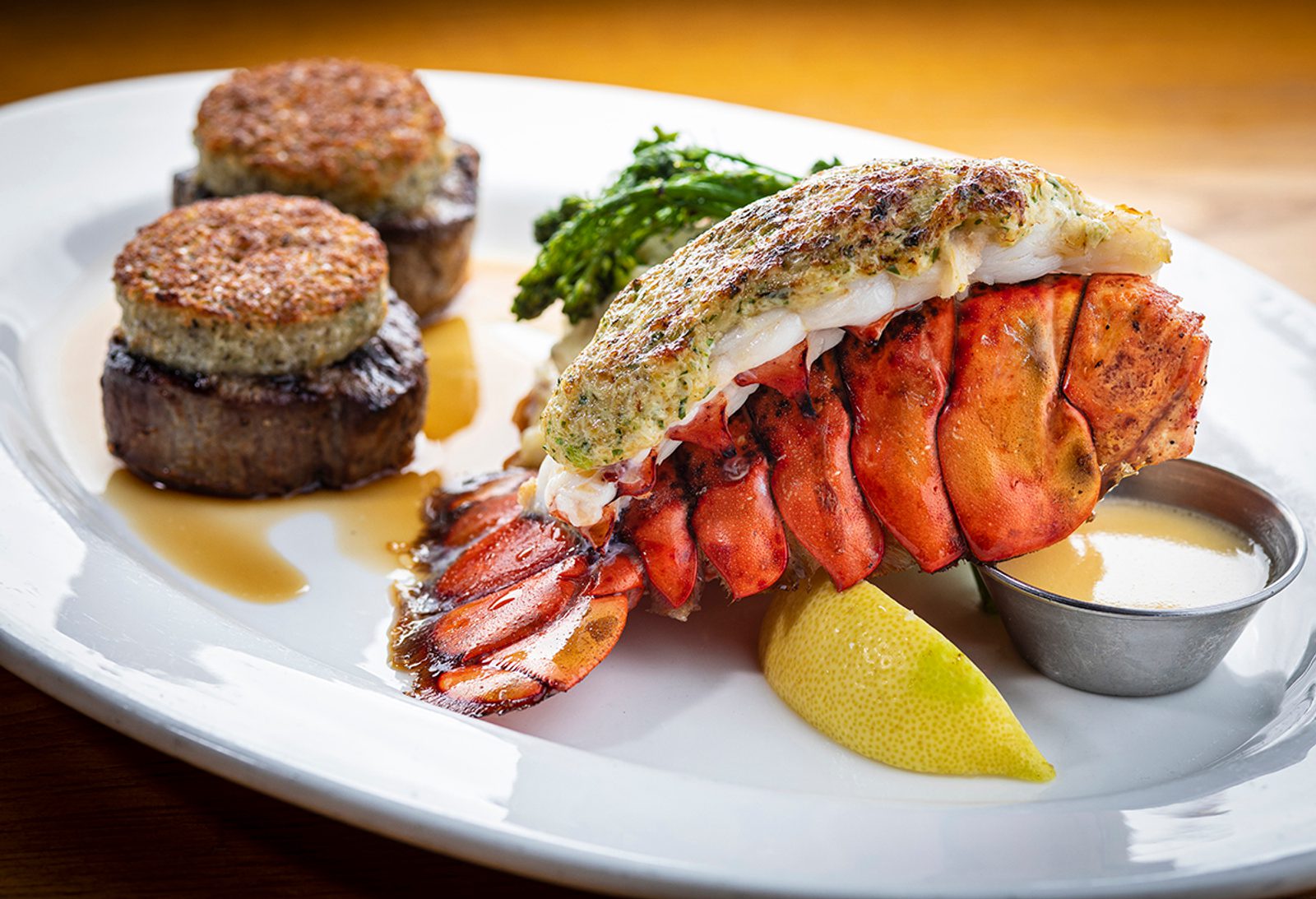 A lobster tail with steak and lemon on a plate.
