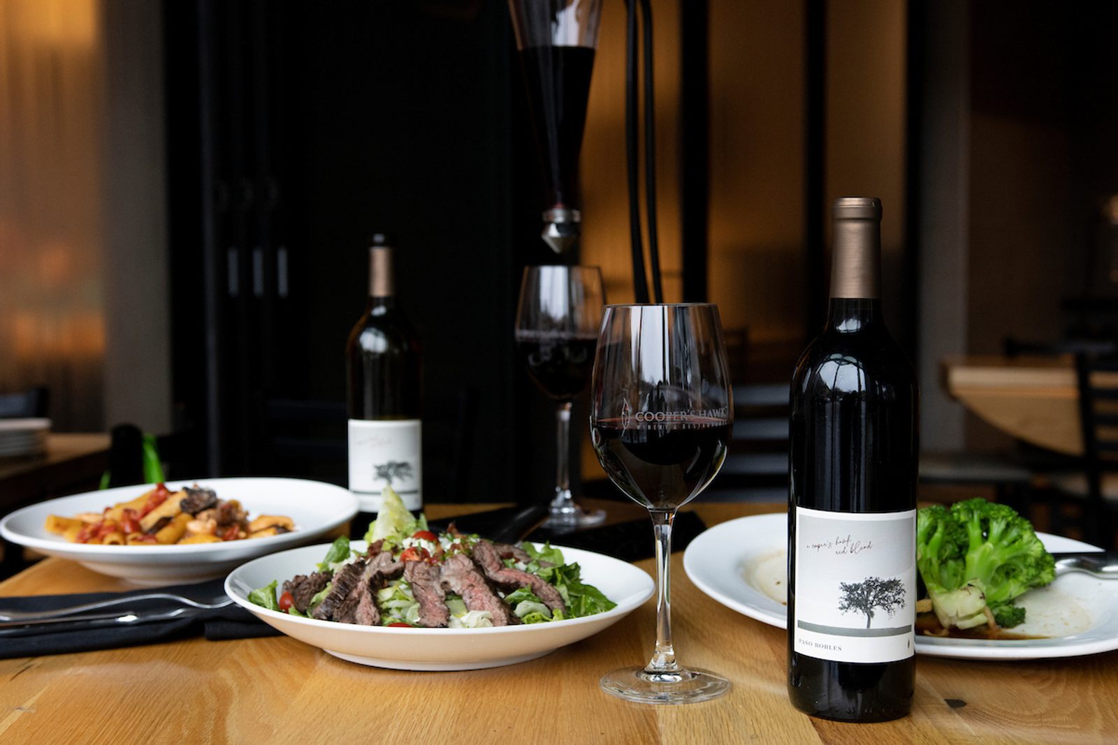 A glass of wine on a table next to a plate of food.