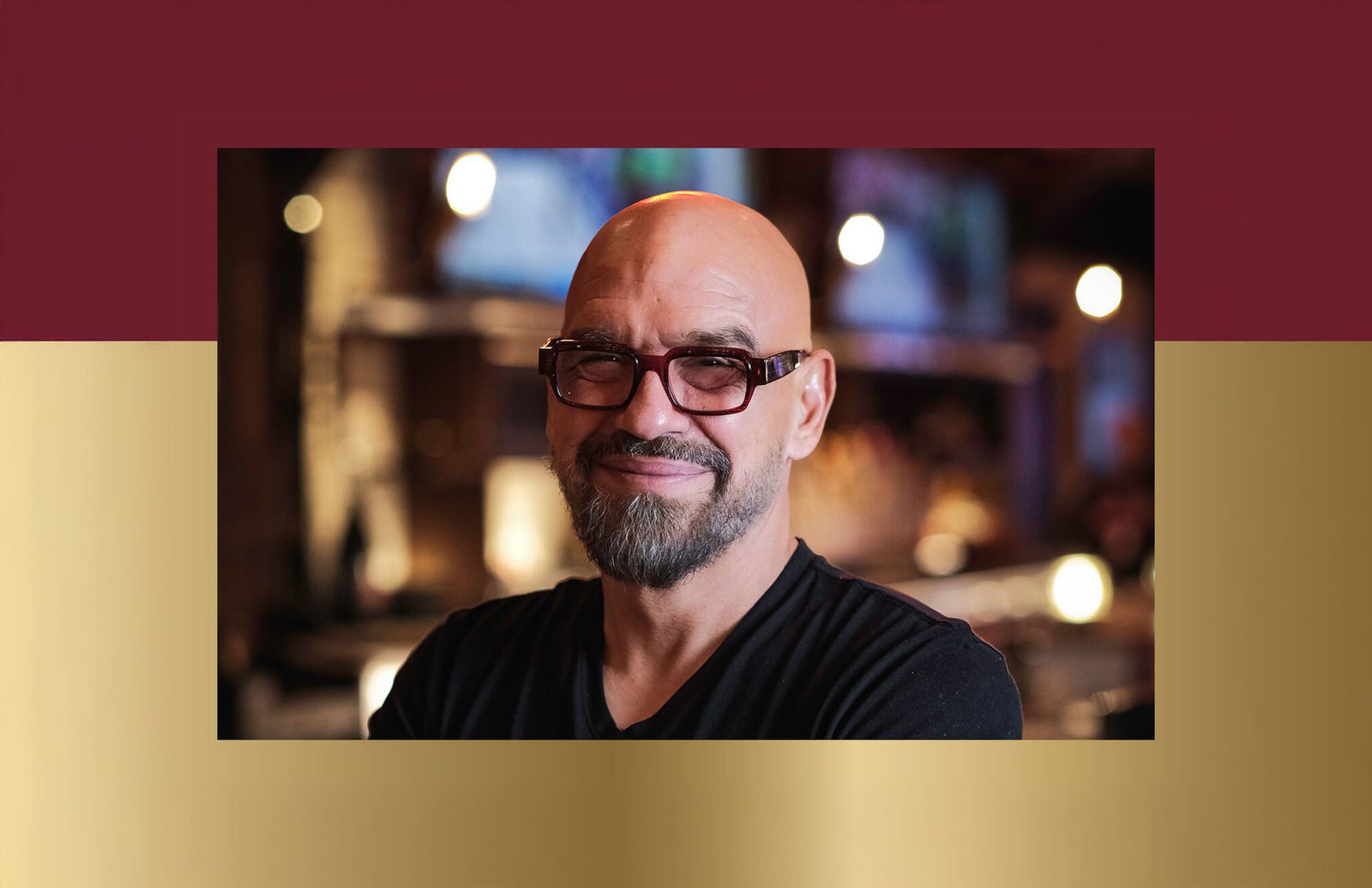 Head-and-shoulders portrait of a person wearing glasses in a dimly lit restaurant or bar interior