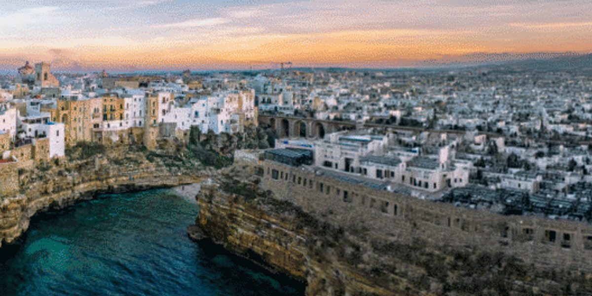 Aerial panoramic view of a coastal town built on limestone cliffs overlooking the sea at sunset