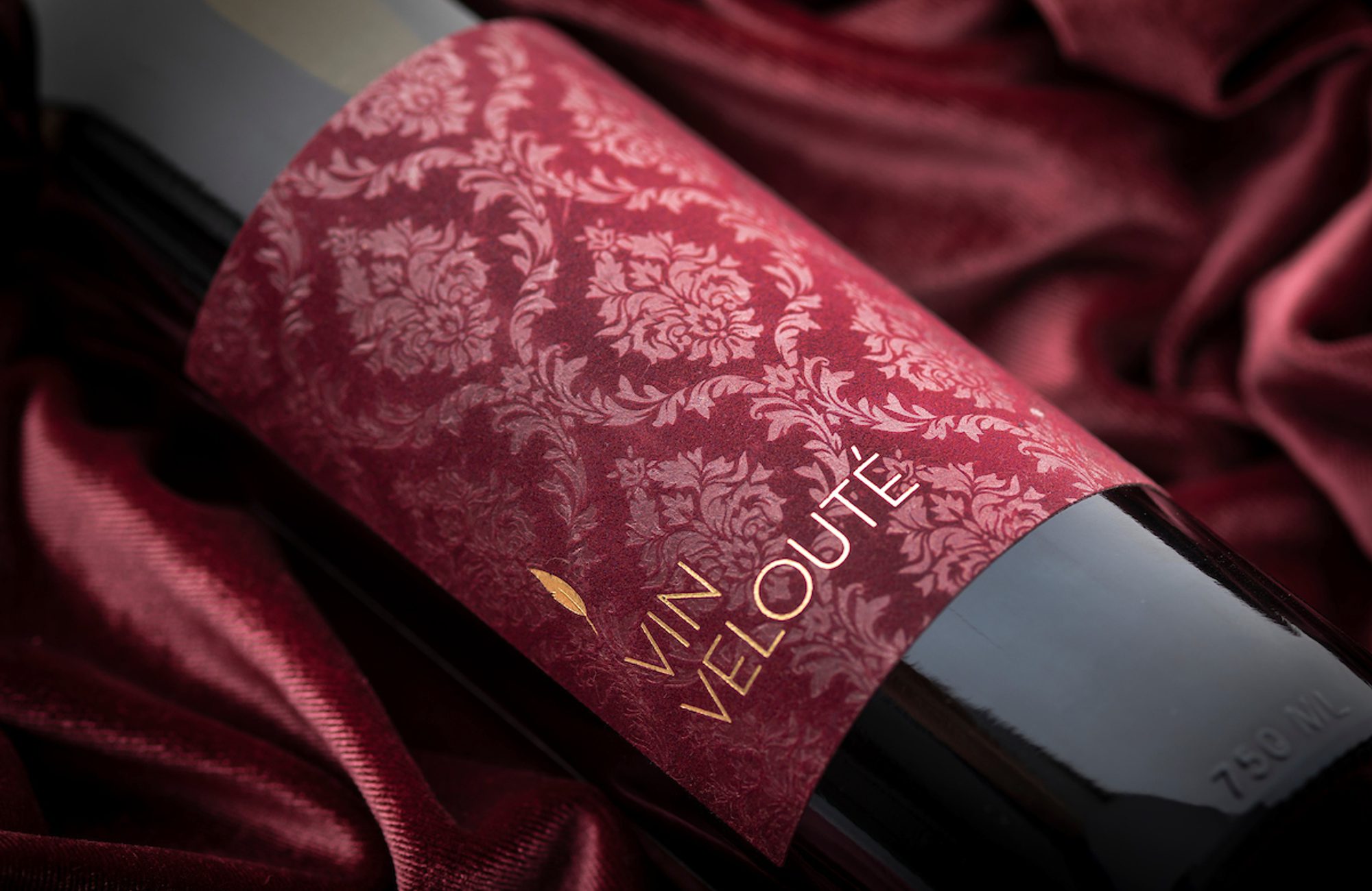 A red wine bottle with a damask pattern on it.