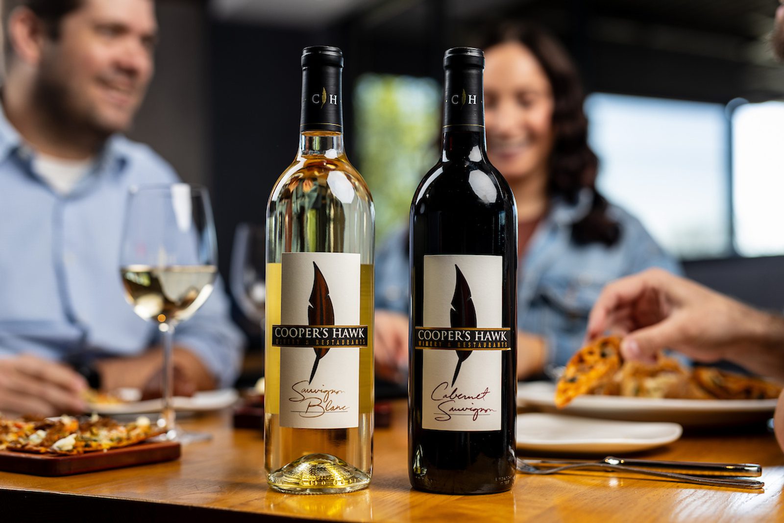People with red and white wine bottles in front of them dining at CH
