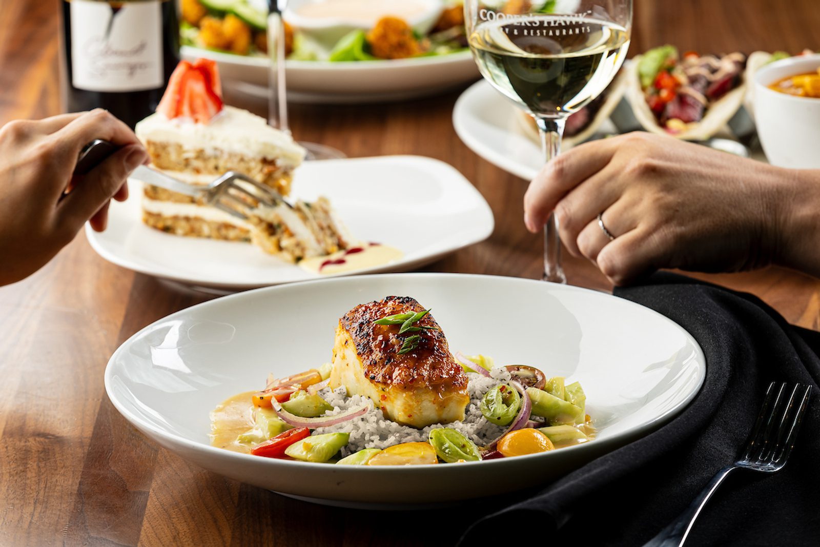 Food image of fish plated and cake in the background