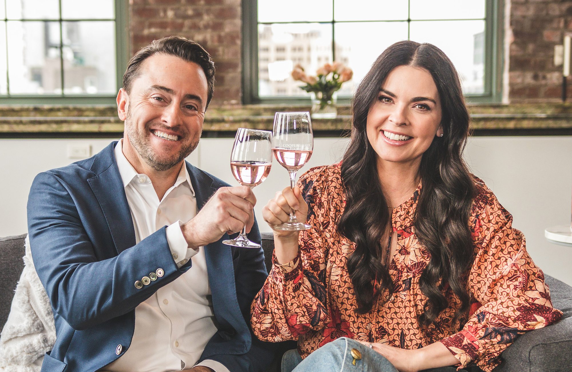 A man and woman holding wine glasses on a couch.