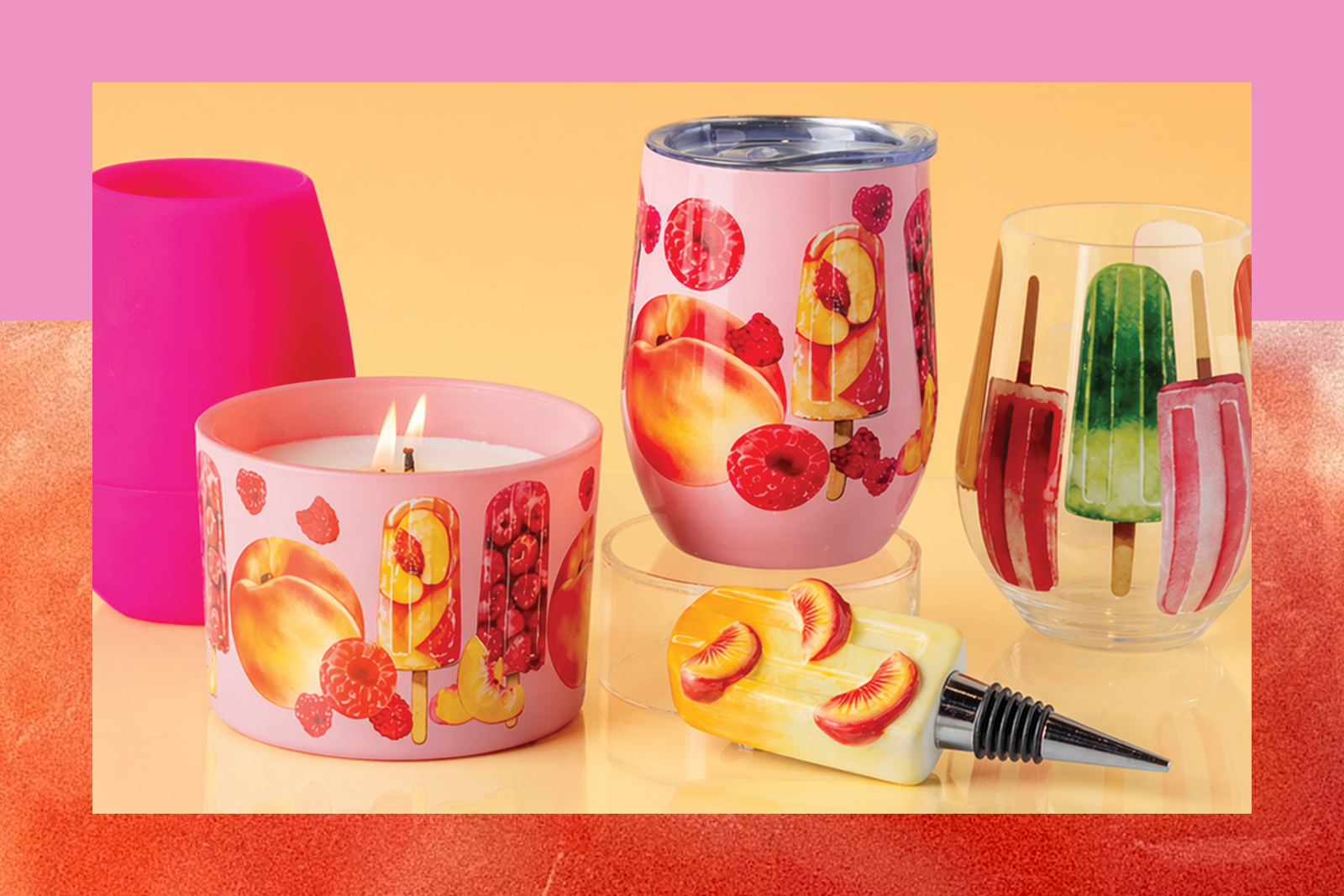 Pink candle, matching insulated tumbler, glass with popsicle prints, and popsicle-shaped bottle stopper on yellow background