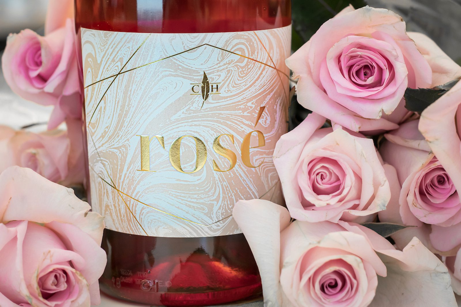 Bottle labeled "LOSC" surrounded by pale pink roses