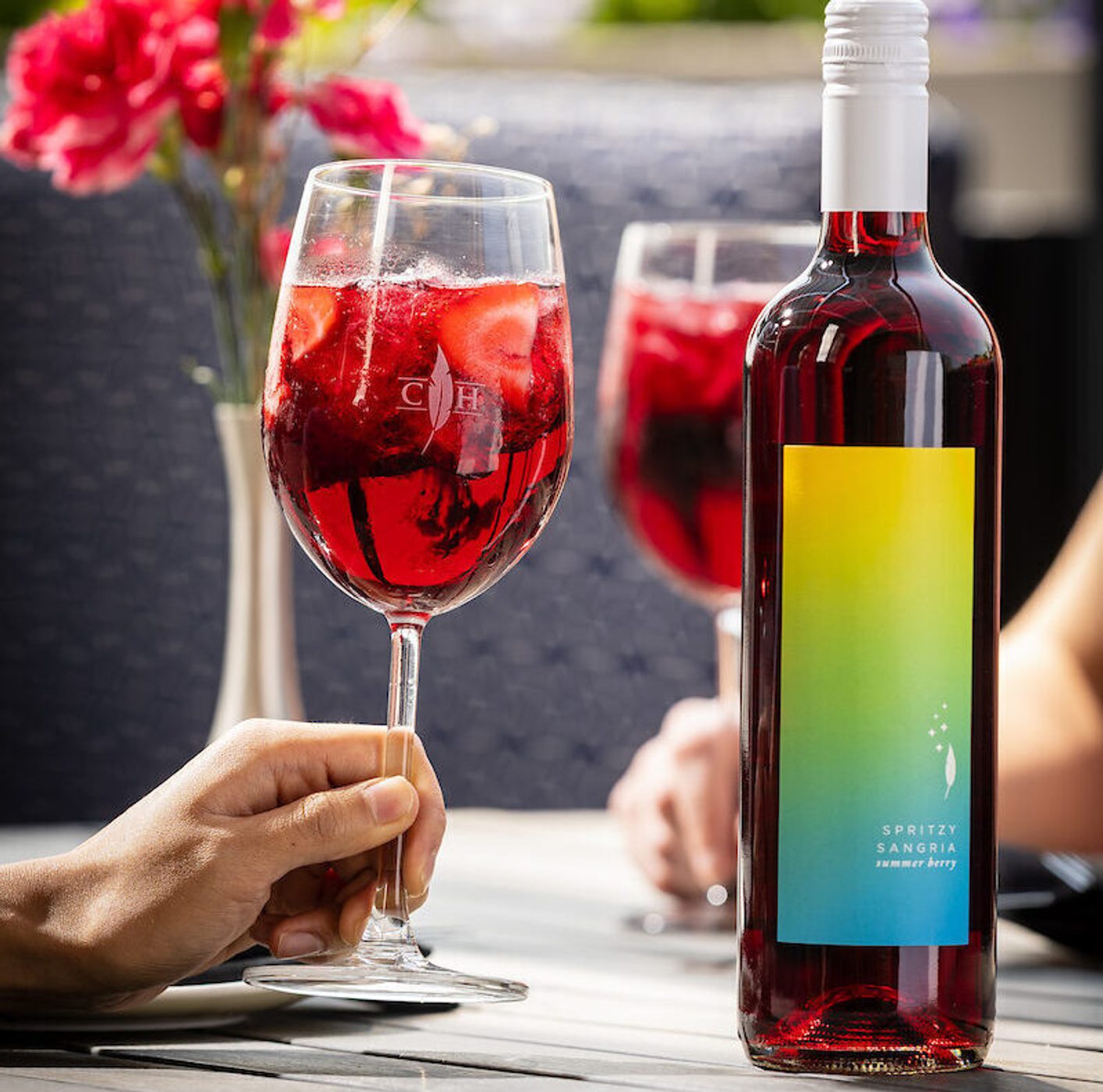 Summer Berry Spritzy Sangria Bottle Image with Glasses of the wine in the background