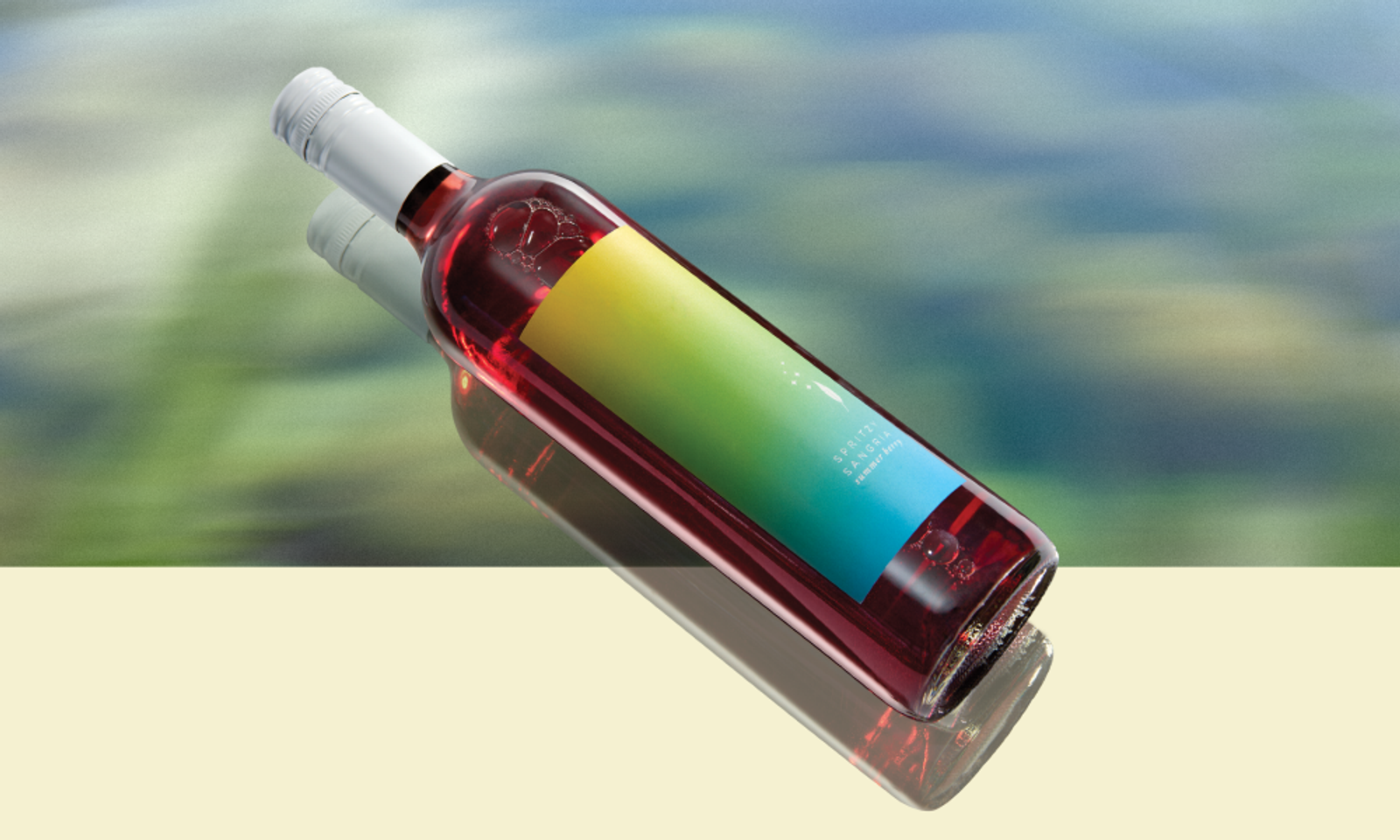 Rosé wine bottle with white screw cap and yellow-to-blue gradient label lying on its side with reflected shadow
