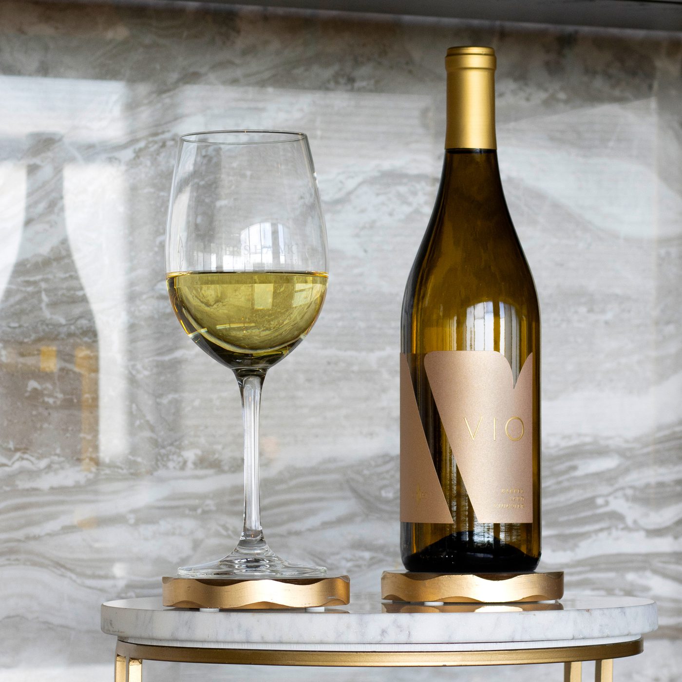 A bottle of wine sits on a table next to a glass.