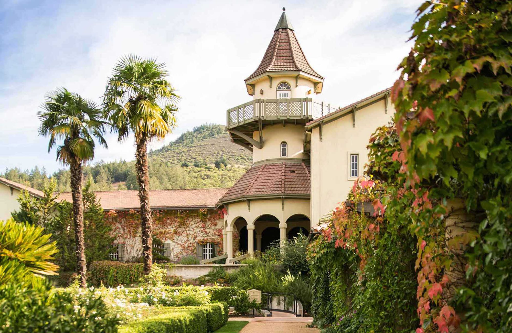 A mansion with a clock tower in the middle of a garden.