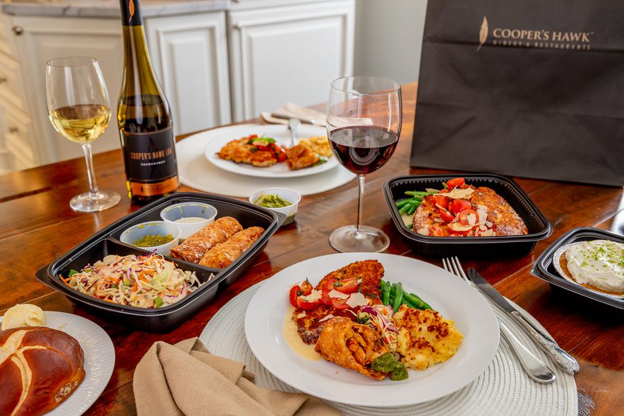 A table with several plates of food and a bottle of wine.