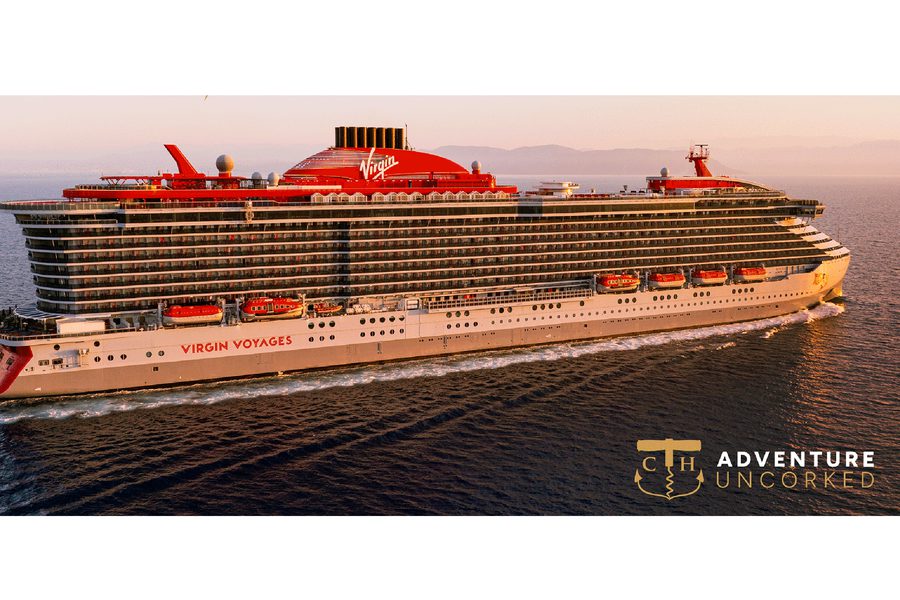 Virgin Voyages cruise ship with red funnel and "Virgin" logo sailing on open water