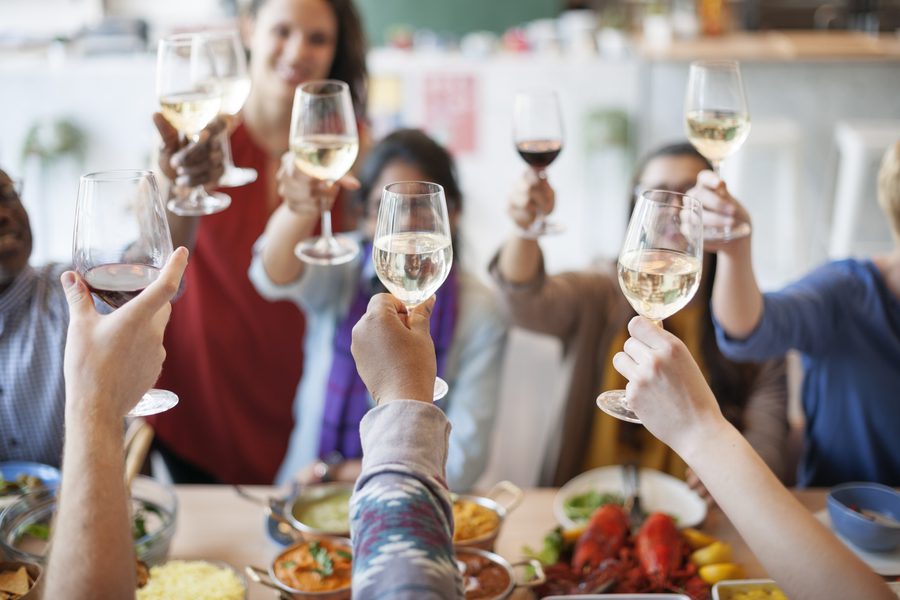 Several friends toast with glasses of wine.
