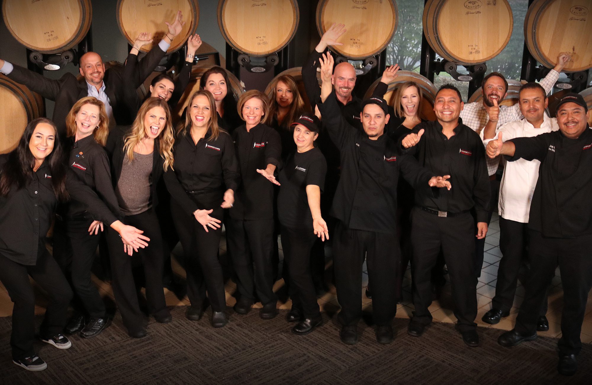 Cooper's Hawk team members grouped for photo in front of wine barrels