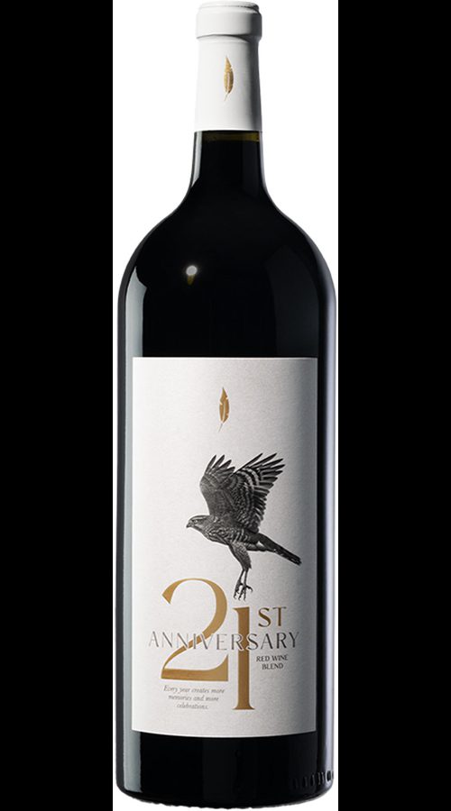 Bottle of red wine with a white label showing a flying bird and “21st Anniversary” in gold and black on a plain white background